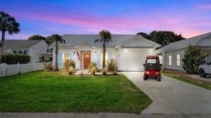 A residential house with a garage, a lawn, and a red golf cart parked in front. - Family & Dog-Friendly Home With Golf Cart And Just Steps to Beach (Panama City Beach)