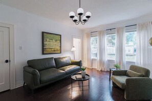 Ein Wohnzimmer mit einer Couch, einem Sessel, einem runden Couchtisch und einem Bild an der Wand.