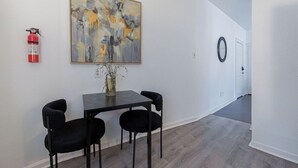 En gang med et spiseområde med bord og stole, en brandslukker og et maleri på væggen.