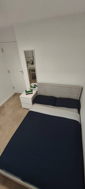 A bedroom with a bed, a nightstand, a mirror, and a closet. - Room-small Double in Quiet House - Chelm (Chelmsford)