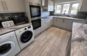 A modern kitchen with a washing machine, oven, microwave, and built-in dishwasher. - Room-small Double in Quiet House - Chelm (Chelmsford)