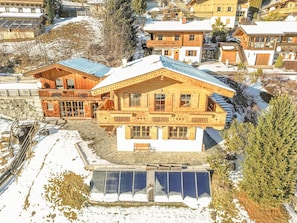 Ein großes Chalet aus Holz mit Balkon, Stein Fundament und schneebedecktem Dach.