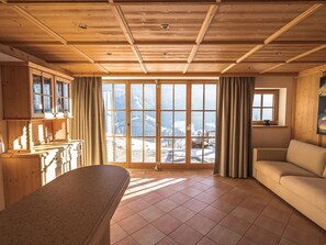 Ein Zimmer mit großem Fenster, Holzboden und einer Couch.
