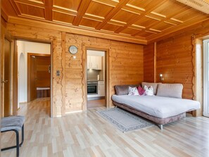 Ein Holzinnenraum mit einem Bett, einer Couch, einer Küche und einer Uhr an der Wand.