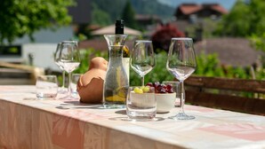 Una mesa con copas de vino, una botella y un cuenco de uvas.