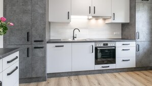Una cocina moderna con armarios blancos, un horno Bosch y una encimera gris.