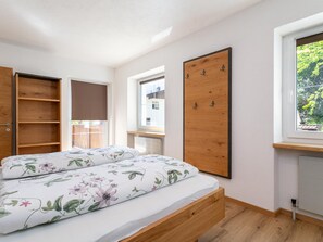 Et soveværelse med seng, et træskab, et vindue og en radiator.