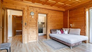 A wooden interior with a bed, a sofa, a kitchen, and a clock on the wall. - Dreamlike vacation apartment with sunny terrace. (Wildschönau)