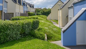 A row of modern, single-story houses with a pathway leading through a well-maintained garden. - R Sidence Les Terrasses de Pentrez M24v (Saint-Nic)