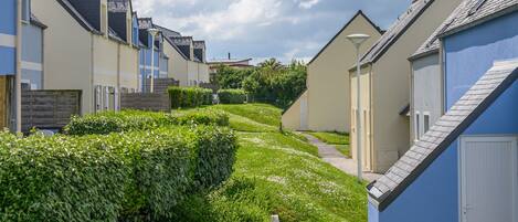 A row of modern, single-story houses with a pathway leading through a well-maintained garden.