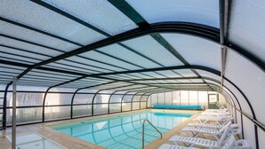An indoor swimming pool with clear glass walls, a blue pool, and white lounge chairs. - R Sidence Les Terrasses de Pentrez M24v (Saint-Nic)