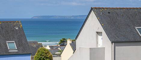 A coastal residential area with houses, a clear sky, and the sea in the background.