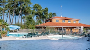 A hotel with a swimming pool, lounge chairs, and a water slide. - Le Domaine des Grands Lacs M48h (Parentis-en-Born)