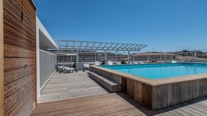 A pool area with a wooden deck, lounge chairs, and a covered seating area. - R Sidence Le Crystal St2s (Cagnes-sur-Mer)