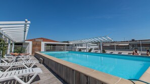 Kattoterassilla on uima-allas, valkoisia aurinkotuoleja ja pergola.