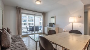 Een hotelkamer met balkon, een eettafel, een bank en een televisie.
