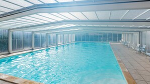 An indoor swimming pool with a glass ceiling, clear water, and a tiled floor. - Le Domaine des Grands Lacs 2p4s (Parentis-en-Born)