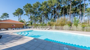 A swimming pool with lounge chairs, a lifeguard tower, and tall trees in the background. - Le Domaine des Grands Lacs M48s (Parentis-en-Born)
