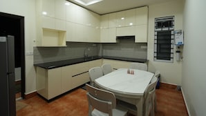 Une cuisine moderne avec des meubles blancs, un plan de travail noir et une table de salle à manger ronde, assortie de chaises.