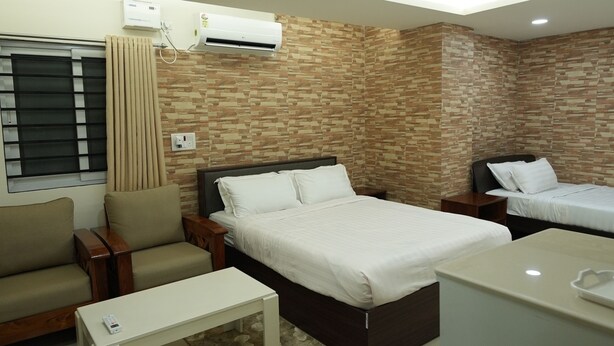 Une chambre d’hôtel moderne équipée d’un lit, d’un canapé, d’une petite table, d’un ventilateur de plafond et d’un appareil de climatisation.