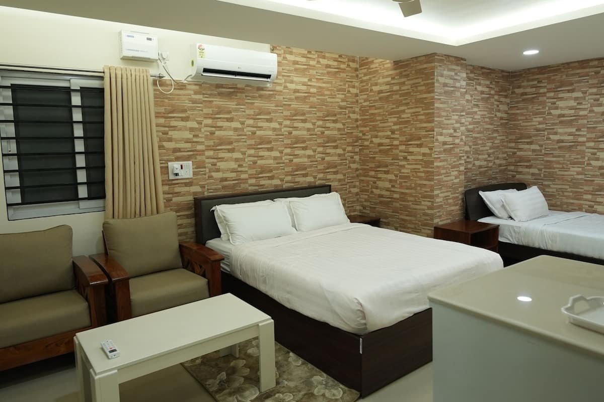 Una habitación de hotel moderna con cama, sofá, una mesita, ventilador de techo y aire acondicionado.