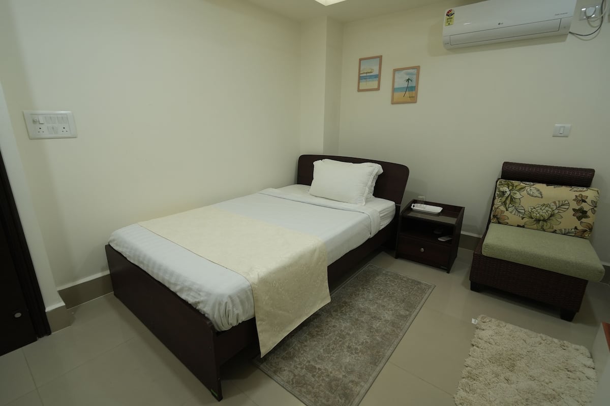 Un dormitorio con cama, mesita de noche, cómoda y aire acondicionado.