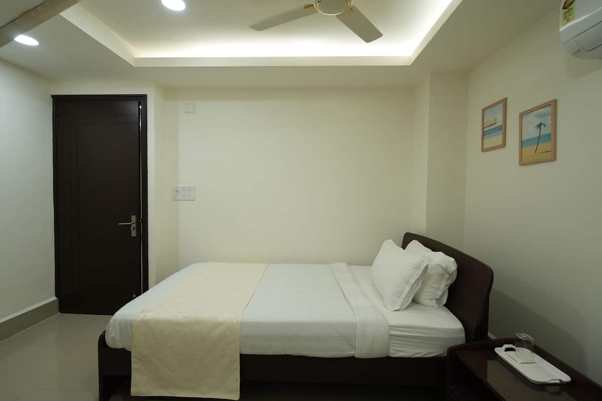 Un dormitorio con cama, ventilador de techo, una puerta y dos cuadros en la pared.
