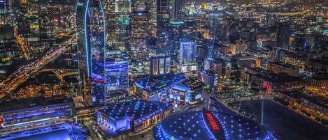 Un paisaje urbano nocturno con edificios iluminados, incluyendo un hotel con una estructura circular grande y un hotel JW Marriott.