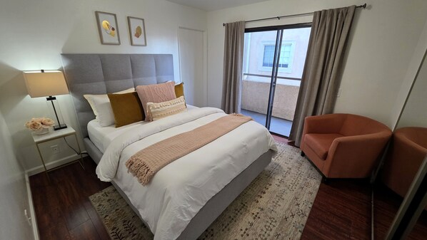 Ein Hotelzimmer mit Bett, Nachttisch, Lampe, Sessel und Blick ins Freie.