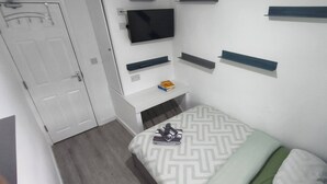 A small, neatly organized bedroom with a bed, a television mounted on the wall, and a door. - Room-cozy Double Room Near City Centre & (Chelmsford)