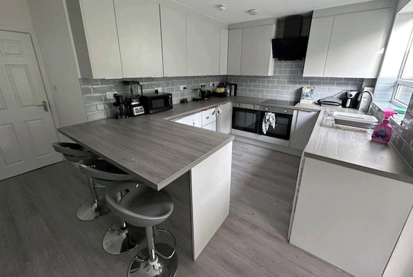 A modern kitchen with white cabinets, a grey countertop, and a built-in oven. - Room-cozy Double Room Near City Centre & (Chelmsford)