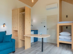 A compact room with a bunk bed, a small table, a sofa, and a wooden wardrobe. - Le Domaine des Mon di res 1p4s (Meyrignac-l'Eglise)