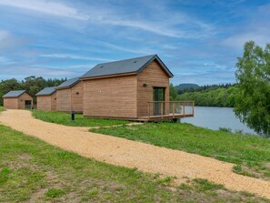 Uma fileira de cabanas de madeira à beira de um lago, com um caminho de cascalho que as leva.