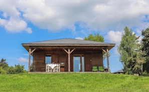 A wooden cabin with a porch, large windows, and a grassy landscape. - Le Domaine des Mon di res 1p4s (Meyrignac-l'Eglise)