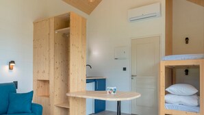 A compact room with a bunk bed, a small table, a sofa, and a wooden wardrobe. - Le Domaine des Mon di res 1p4v (Meyrignac-l'Eglise)