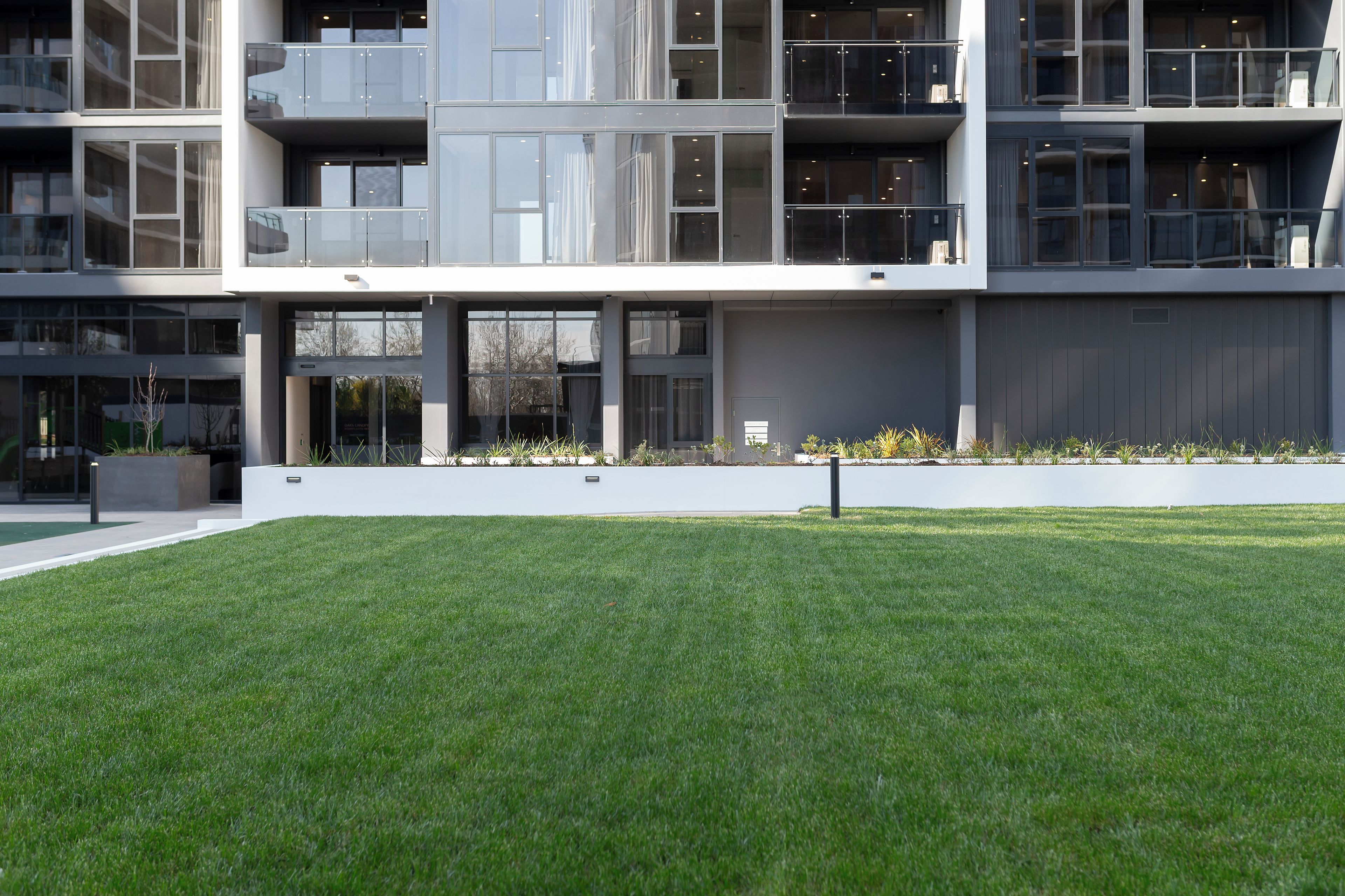 Un bâtiment moderne à plusieurs étages, doté de grandes fenêtres et d’une pelouse bien entretenue à l’avant.