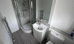 A modern bathroom with a glass shower enclosure, a white sink, and a toilet. - Room-small Cozy Room in Chelmsford Sprin (Chelmsford)