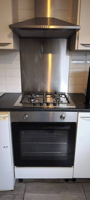 Cozinha com coifa de aço inoxidável, fogão a gás e forno.