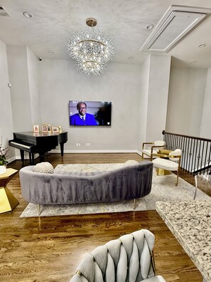 Ein modernes Wohnzimmer mit Flachbildfernseher, einem Flügel, einer bequemen Couch und einer Treppe.