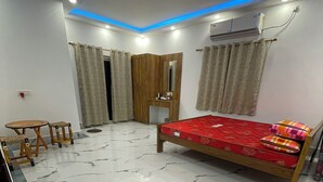 A bedroom with a bed, vanity, and a ceiling fan. - Jonaki Shantiniketan (Bolpur)