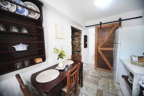 Uma sala de jantar com uma mesa de madeira, cadeiras, um vaso de flores e uma parede de pedra.