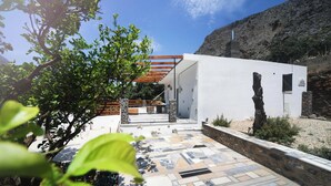 A modern building with a stone facade, a wooden pergola, and a tiled patio area. - Cozy 1-bedroom apartment in charming Kalymnos with AC (Kalymnos)
