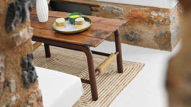 A cozy seating area with a stone bench, a wooden table with a placemat, and a white vase with pampas grass. - Cozy 1-bedroom apartment in charming Kalymnos with AC (Kalymnos)