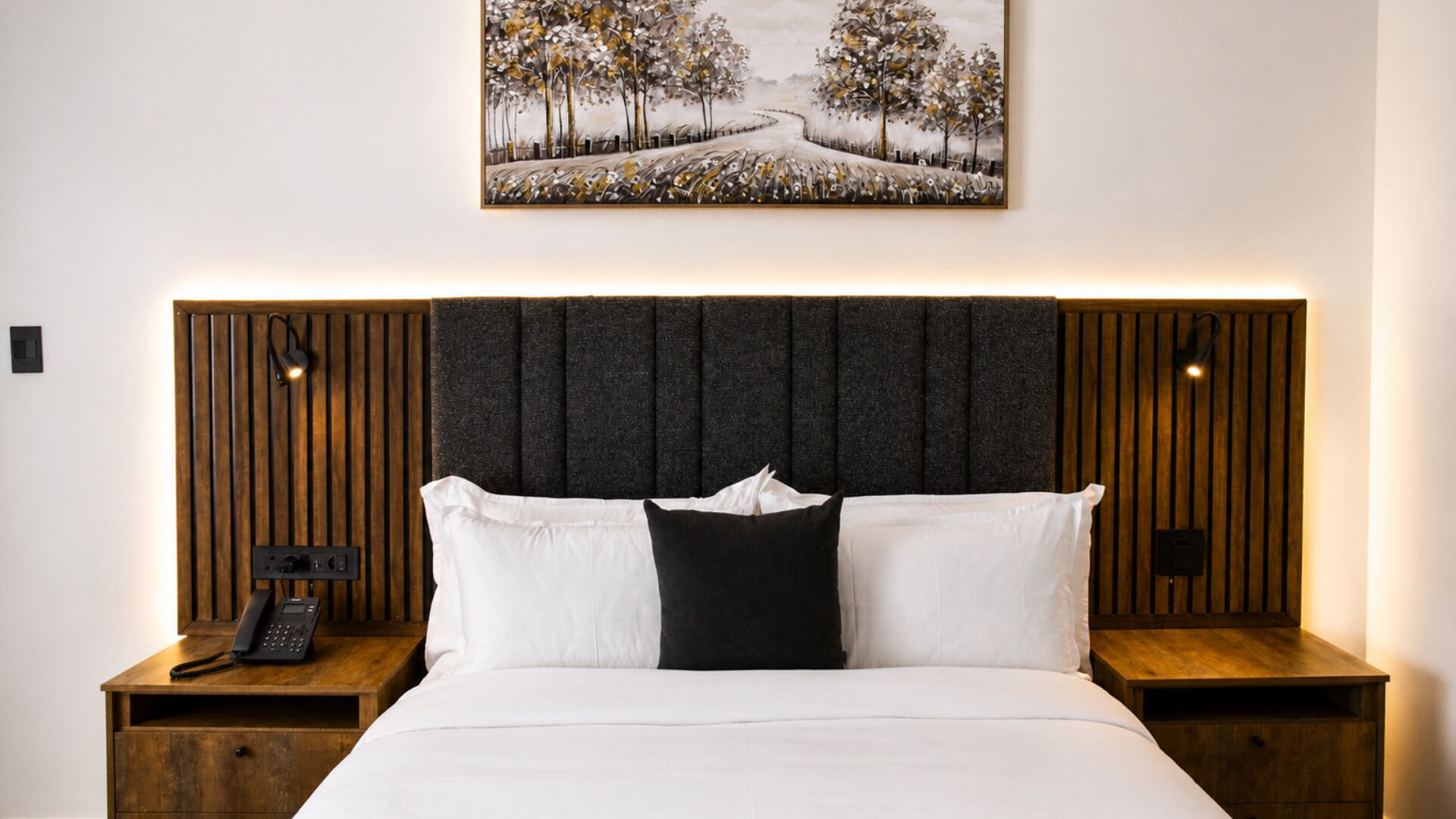 A hotel room with a bed, two nightstands, a telephone, and a painting above the bed.