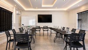A conference room with a long table, chairs, a whiteboard, and a flat-screen TV. - Regent Heights Hotel (Ruiterhof, Sandton)