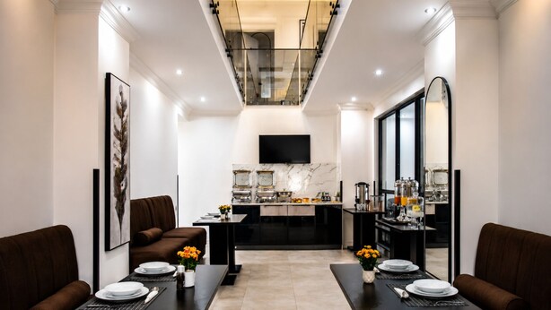 A modern kitchen with marble countertops, a central island, and a flat-screen TV mounted above the island.