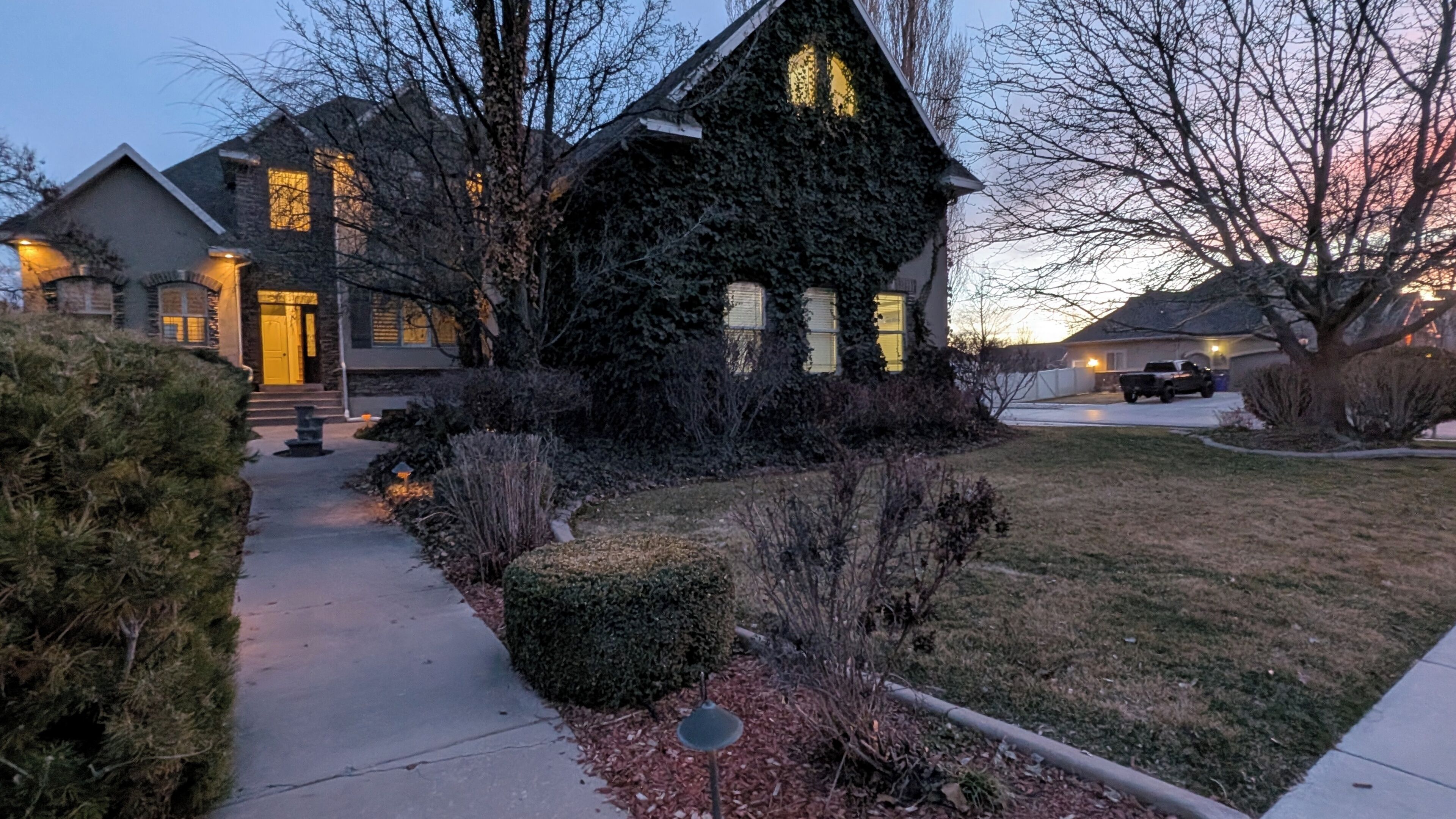 A residential house with a well-maintained lawn, a driveway, and a visible front yard with a birdbath.
