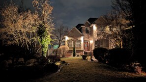 A two-story house with a stone facade, a front porch, and a well-lit entrance.