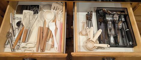 A drawer with kitchen utensils and tools, including whisks, spatulas, and measuring spoons.