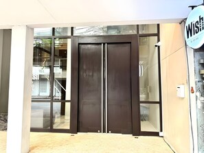 A double door entrance with glass panels, a sign reading 'Wish,' and a visible staircase to the left. - Wish Inn Silom (Bangkok)